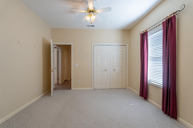  - unfurnished bedroom featuring multiple windows, light carpet, a ceiling fan, and a closet