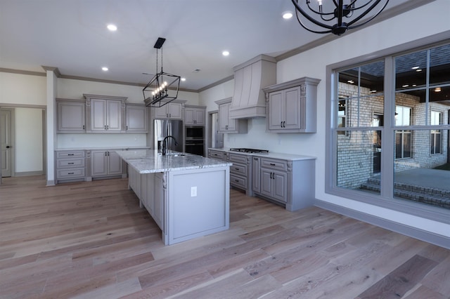 kitchen with a notable chandelier, light hardwood / wood-style floors, custom range hood, and stainless steel appliances