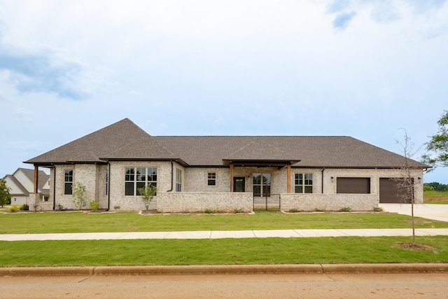 view of front facade with a front lawn, brick siding, a garage, and driveway