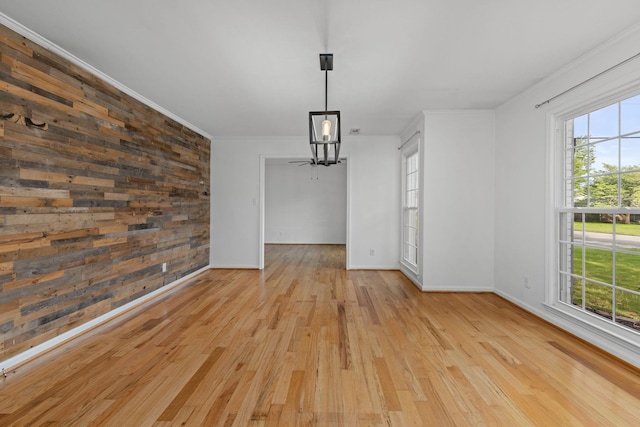  - unfurnished dining area featuring healthy amount of natural light, wood finished floors, baseboards, crown molding, and wood walls