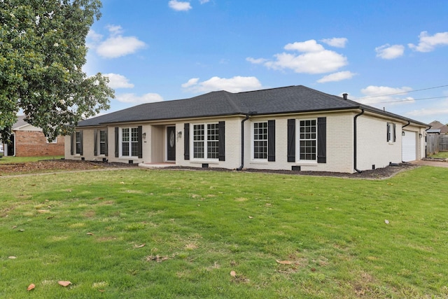  - back of house with a garage, brick siding, and a lawn