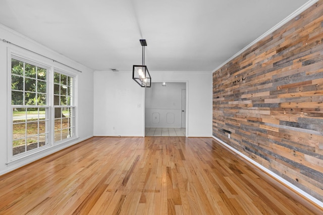  - unfurnished dining area with crown molding, wooden walls, wood finished floors, and baseboards