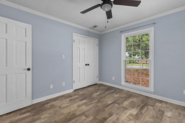  - unfurnished bedroom featuring wood finished floors, baseboards, crown molding, a closet, and a ceiling fan