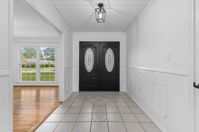  - foyer featuring light tile patterned flooring and crown molding