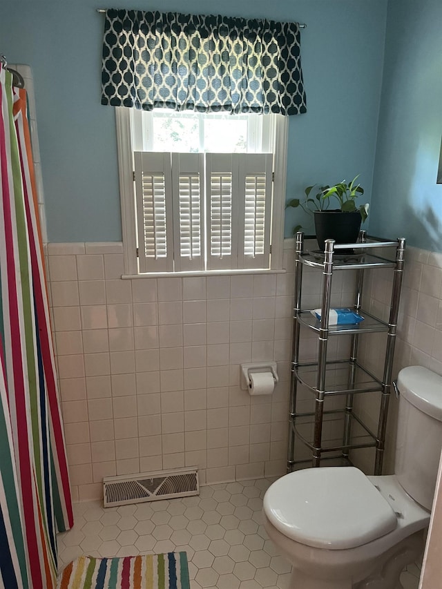  - full bathroom with toilet, tile walls, healthy amount of natural light, wainscoting, and a shower with shower curtain