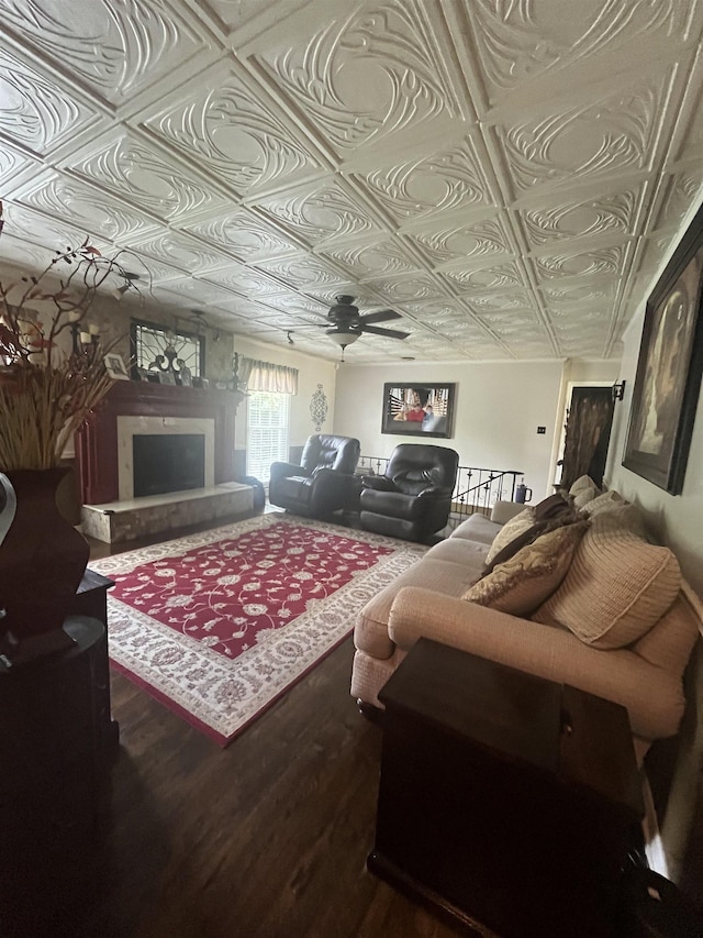  - living room with an ornate ceiling, wood finished floors, a ceiling fan, and a fireplace with raised hearth