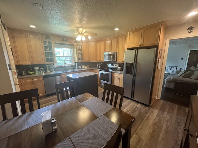  - kitchen with stainless steel appliances, glass insert cabinets, tasteful backsplash, wood finished floors, and recessed lighting