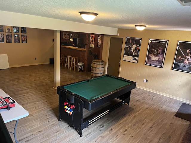  - game room with a bar, pool table, wood finished floors, baseboards, and a textured ceiling