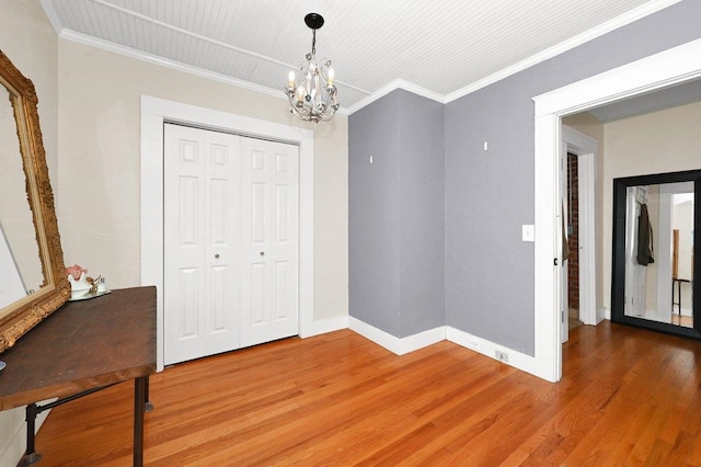  - unfurnished dining area featuring baseboards, light wood finished floors, crown molding, and a notable chandelier