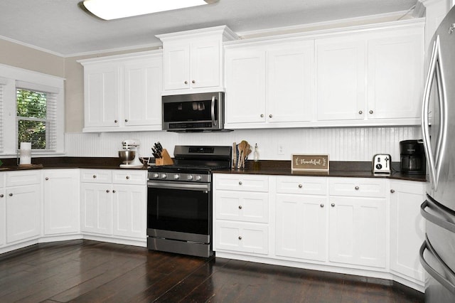  - kitchen with crown molding, dark countertops, dark wood-style floors, stainless steel appliances, and white cabinetry
