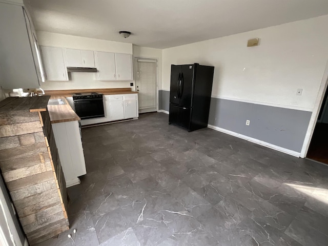 kitchen with black refrigerator, white cabinetry, sink, wooden counters, and stove