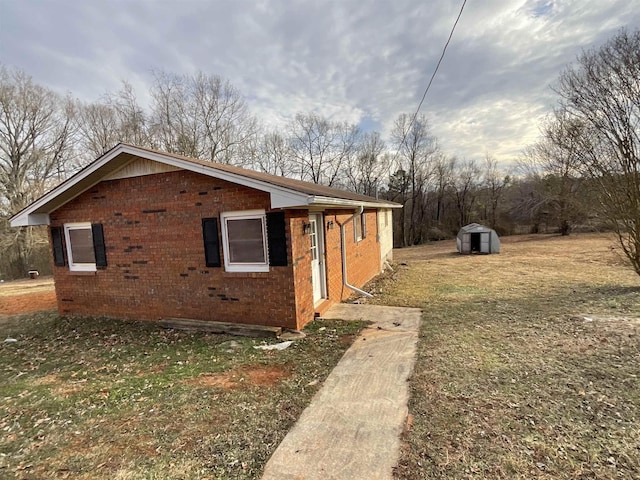 view of side of home featuring a yard and a shed