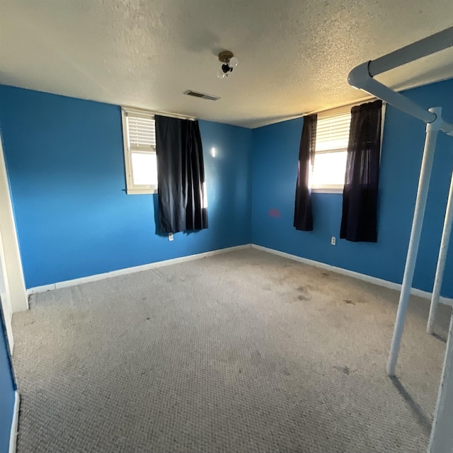 carpeted spare room featuring a textured ceiling