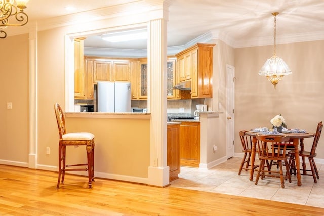 kitchen featuring white refrigerator, kitchen peninsula, crown molding, light brown cabinetry, and light wood-type flooring