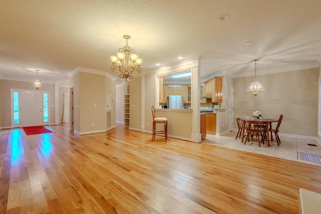 unfurnished living room featuring a chandelier, light hardwood / wood-style floors, and crown molding