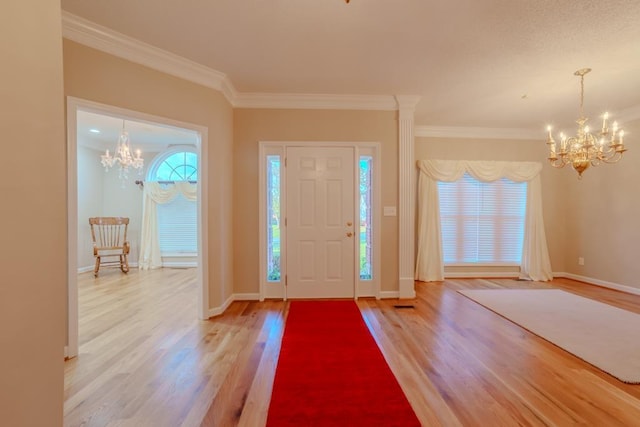 entryway with ornamental molding, a notable chandelier, and hardwood / wood-style floors