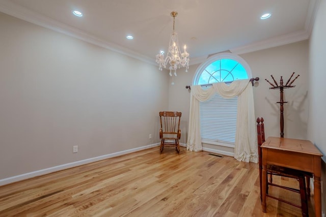 sitting room with light wood-type flooring, an inviting chandelier, and ornamental molding