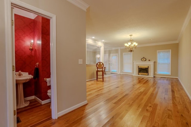 living room featuring sink, hardwood / wood-style flooring, ornamental molding, and a notable chandelier