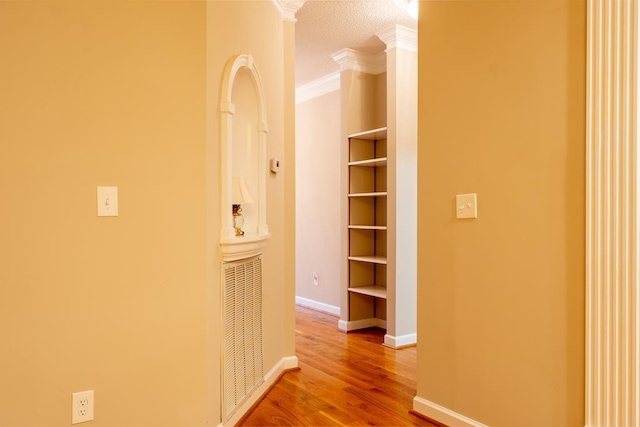 corridor featuring hardwood / wood-style floors, crown molding, and a textured ceiling