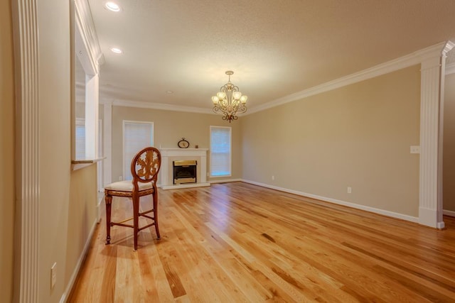 unfurnished living room with an inviting chandelier, light hardwood / wood-style flooring, ornamental molding, and ornate columns