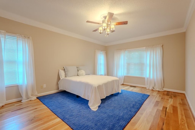 bedroom with multiple windows, hardwood / wood-style floors, ceiling fan, and crown molding