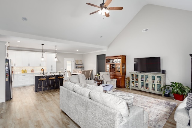 living room featuring ceiling fan, high vaulted ceiling, and light hardwood / wood-style floors