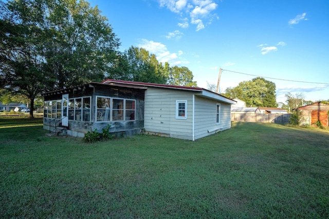 rear view of property with a lawn and a sunroom