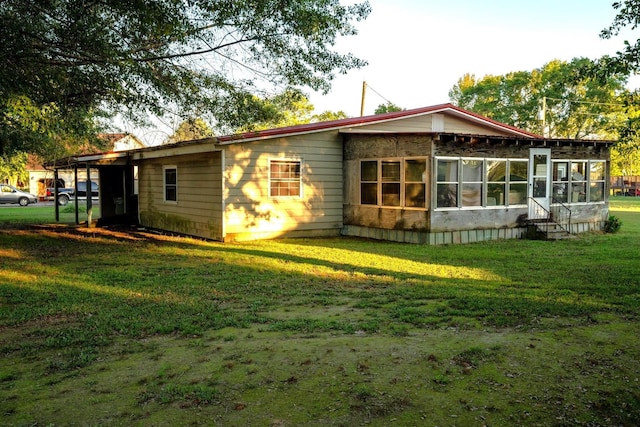 rear view of property with a yard and a sunroom