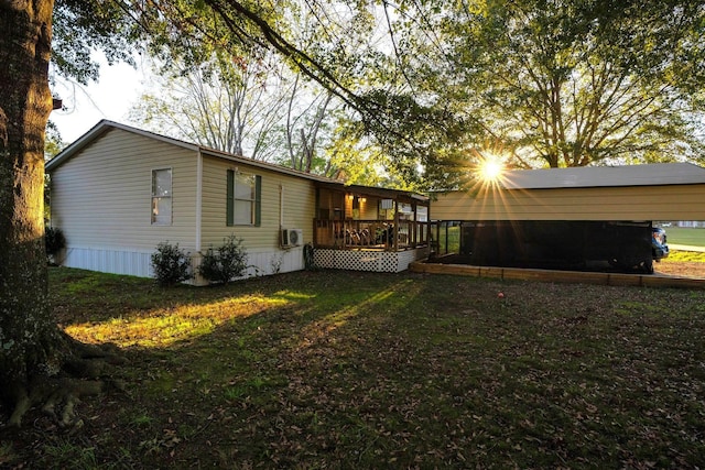 rear view of property with a yard, a deck, and a carport