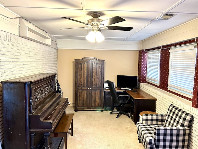 carpeted office space with visible vents, brick wall, and a ceiling fan