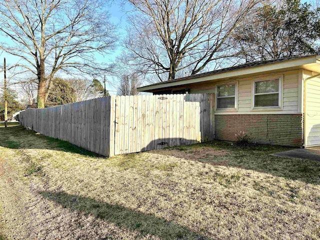 view of property exterior with a yard, fence, and brick siding