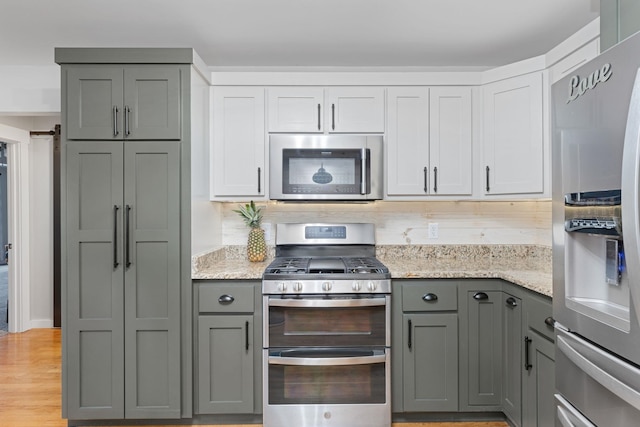 kitchen featuring gray cabinetry, stainless steel appliances, light stone countertops, light hardwood / wood-style floors, and white cabinets