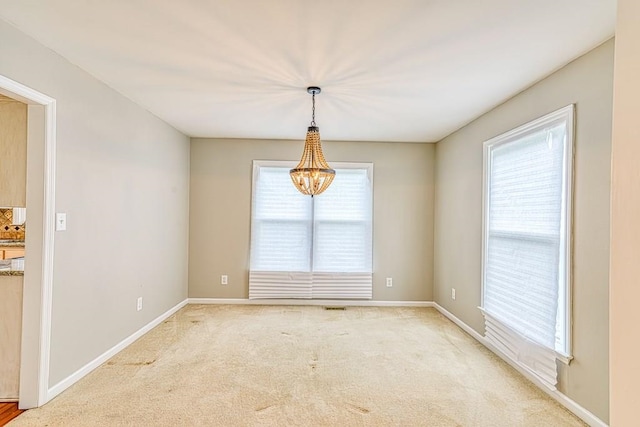 unfurnished room featuring a notable chandelier and light carpet