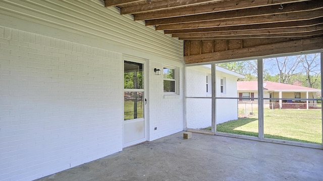 unfurnished sunroom featuring beamed ceiling and a wealth of natural light
