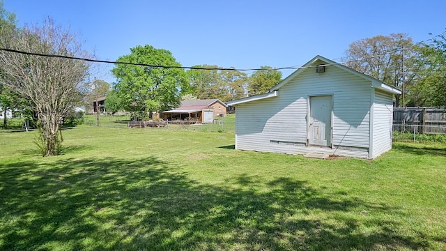 back of property featuring a yard, fence, and an outdoor structure