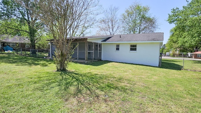 rear view of house featuring a sunroom, fence, and a lawn