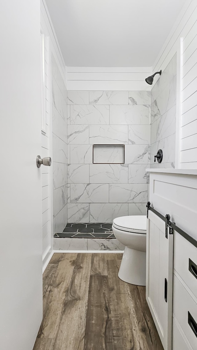 full bath featuring toilet, vanity, a stall shower, and wood finished floors