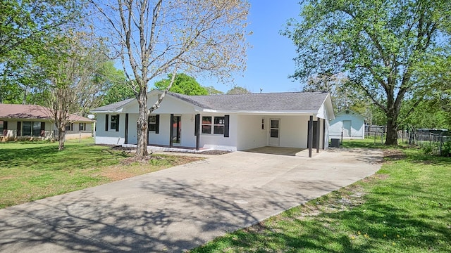 view of front of property with a carport, concrete driveway, fence, stucco siding, and a front lawn
