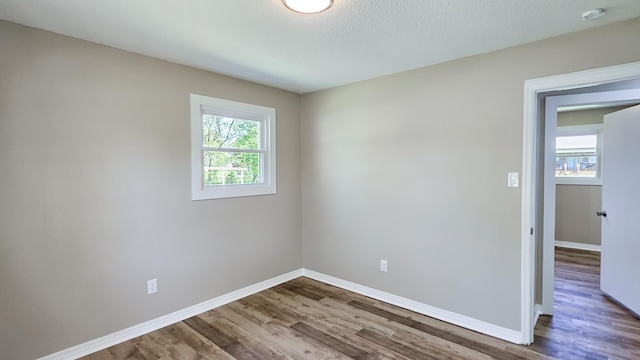 unfurnished room with baseboards, wood finished floors, and a textured ceiling