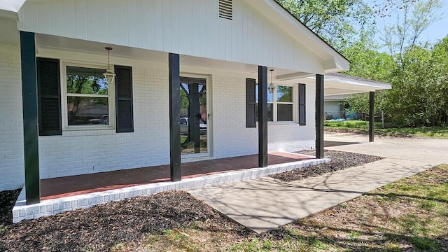 view of side of home with a carport, a porch, and brick siding