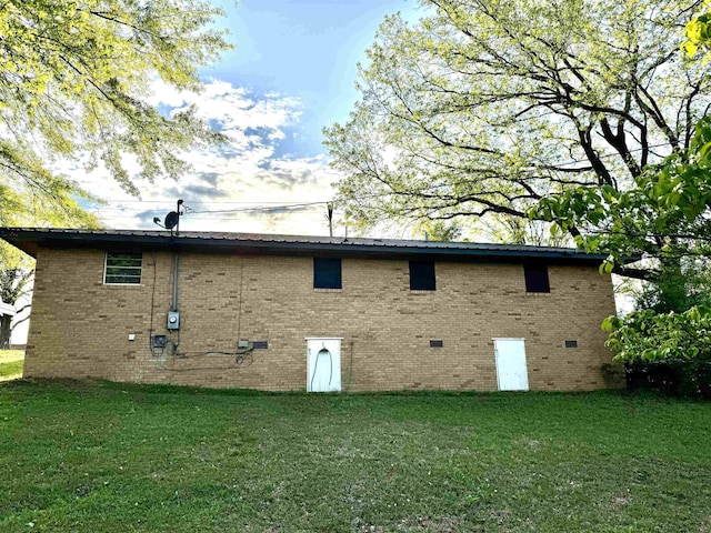 back of house featuring a lawn and brick siding
