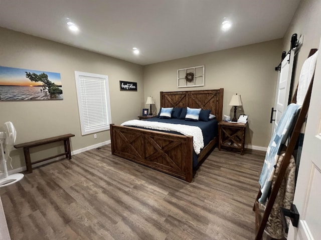 bedroom with a barn door and hardwood / wood-style floors