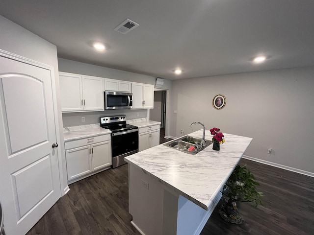 kitchen featuring sink, dark wood-type flooring, a center island with sink, white cabinets, and appliances with stainless steel finishes