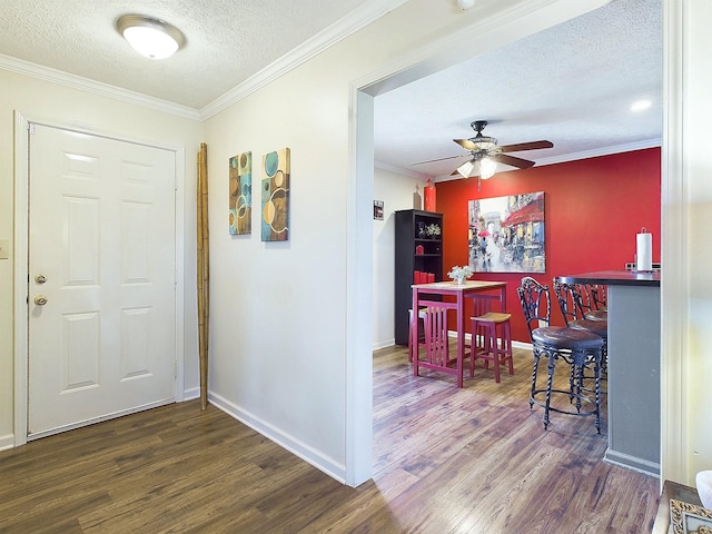 entrance foyer with crown molding, a dry bar, ceiling fan, a textured ceiling, and wood finished floors