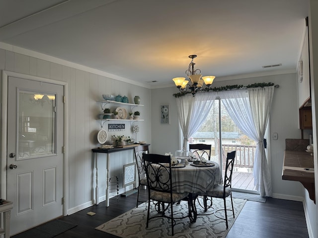  - dining area with a chandelier, ornamental molding, dark wood-type flooring, and baseboards