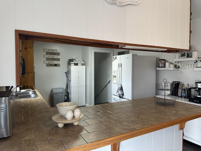 - kitchen with white refrigerator with ice dispenser, a sink, tile countertops, and white cabinets