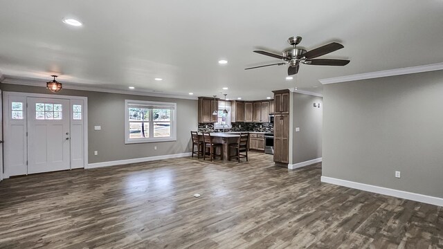 unfurnished living room featuring crown molding, a fireplace, ceiling fan, and dark hardwood / wood-style floors