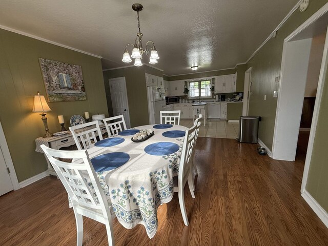  - dining room featuring ornamental molding, a chandelier, wood finished floors, baseboards, and a textured ceiling
