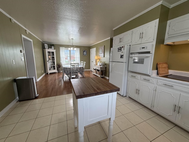  - kitchen featuring white appliances, butcher block countertops, crown molding, white cabinetry, and light tile patterned floors