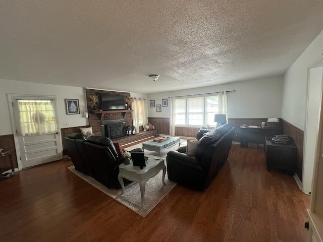  - living room with a textured ceiling, a wainscoted wall, wood finished floors, and a brick fireplace